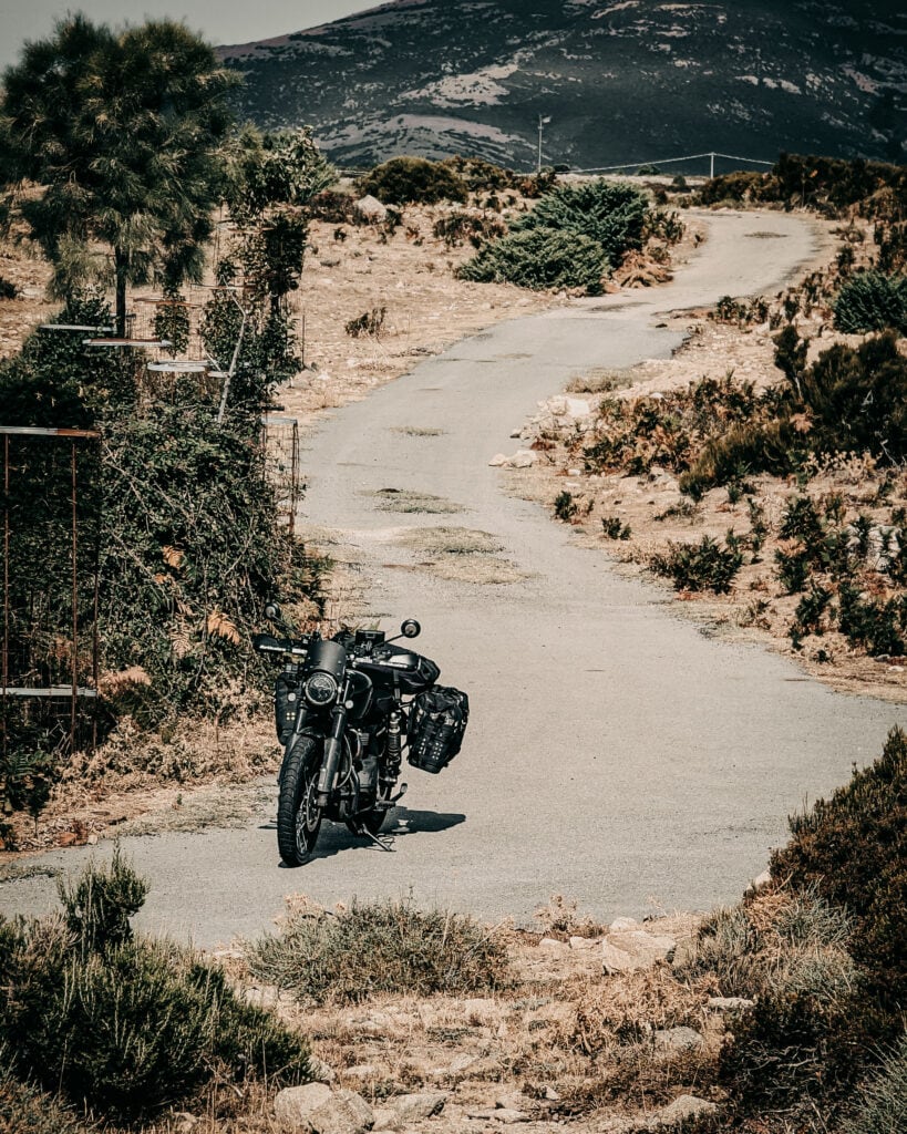Motorcycle parked on a winding mountain road surrounded by nature.