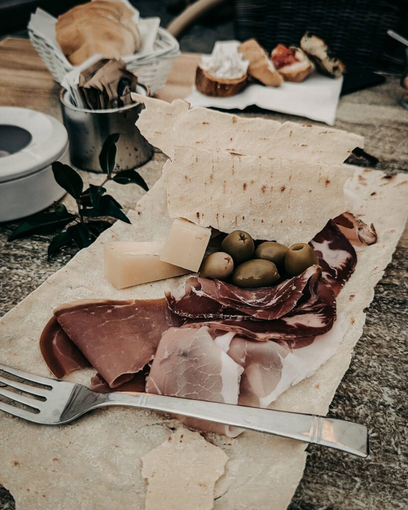 Italian charcuterie and cheese platter with olives and bread on rustic table.