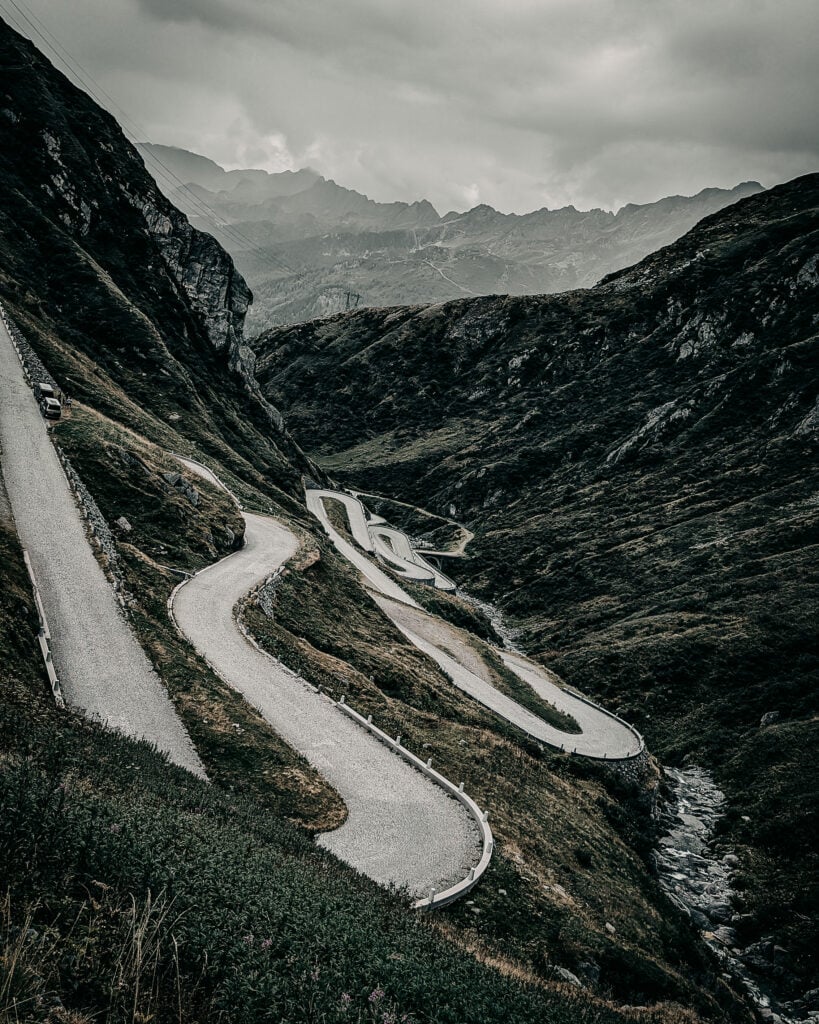 Winding mountain road with sharp hairpin turns in a rugged landscape.