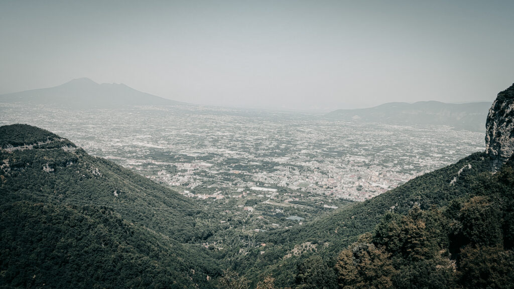 Panoramic view of mountains overlooking a cityscape in the distance.