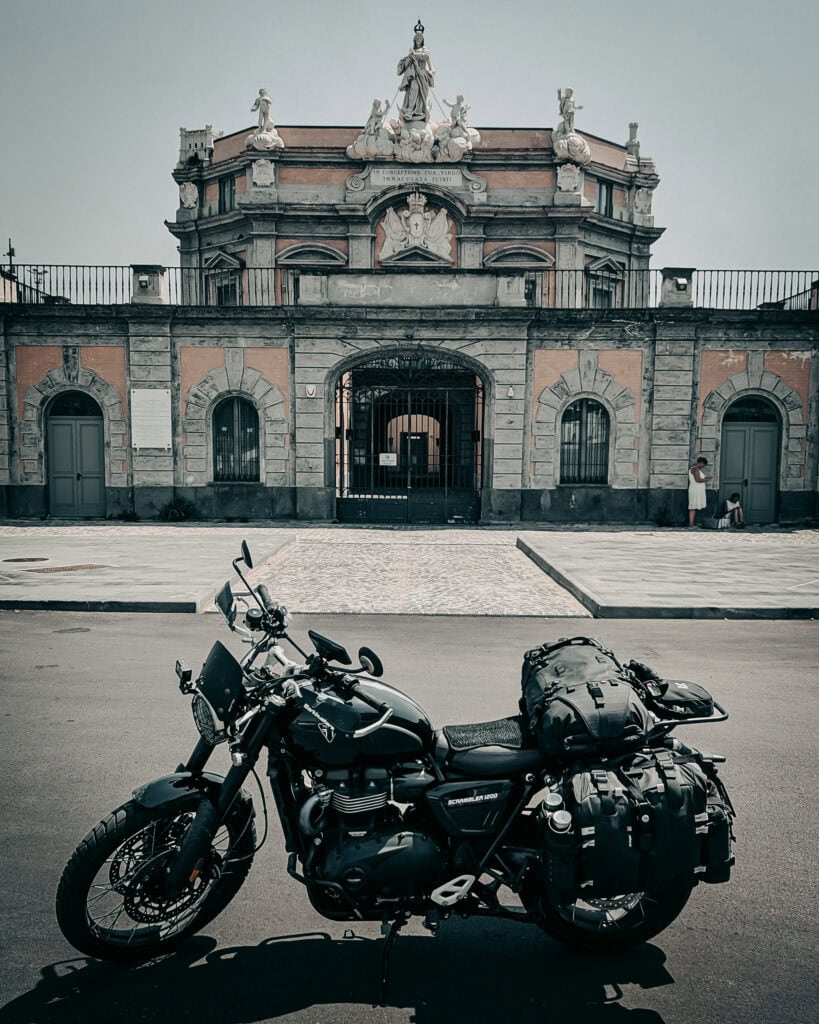 Motorcycle parked in front of historic building with ornate architecture.