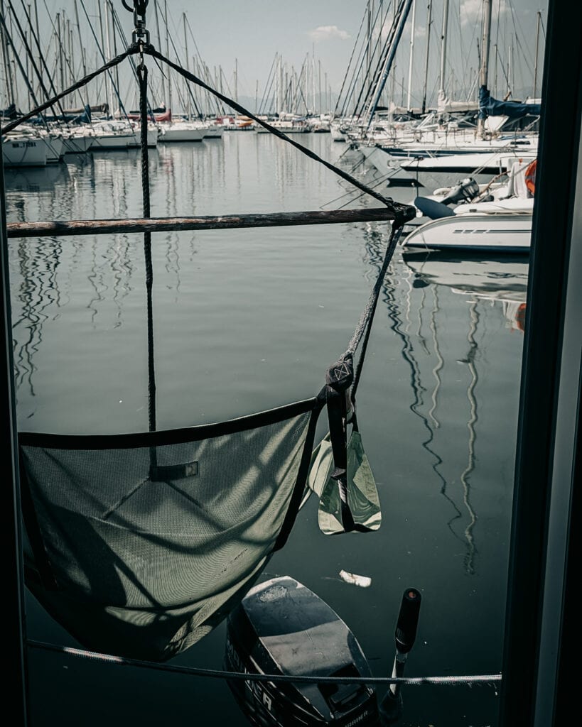 Relaxing hammock on a boat at a marina with sailboats and yachts.