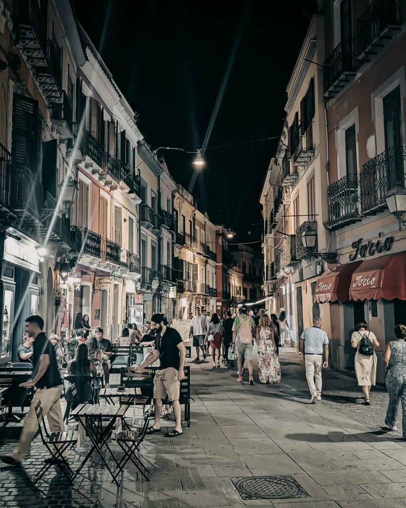Night street scene with people dining and walking in a European city.