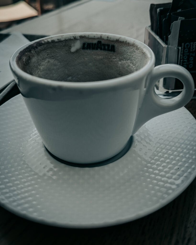 A steaming cup of coffee in a white ceramic mug on a table.
