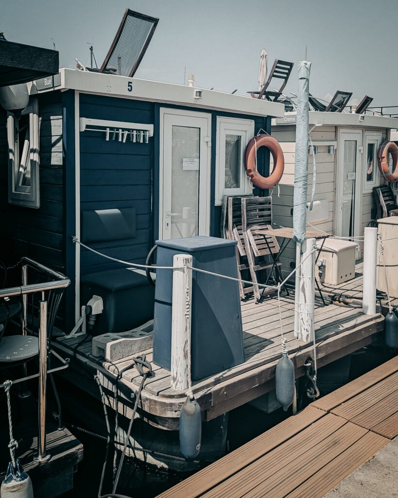 Modern houseboat with deck chairs, life rings, and solar panels.