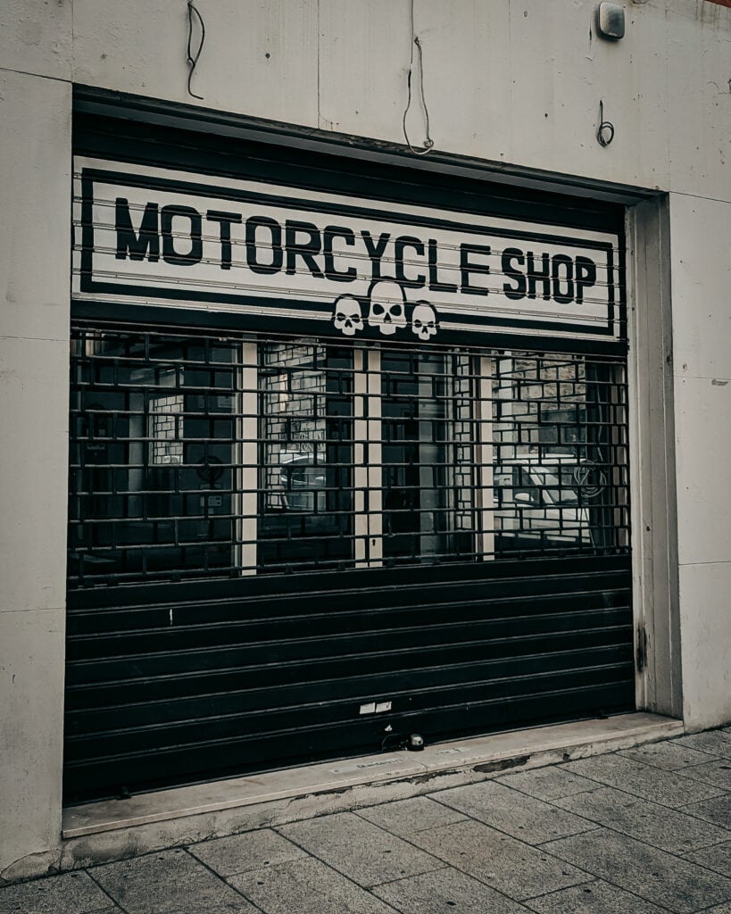Motorcycle shop entrance with black rolling shutter and skull decorations.