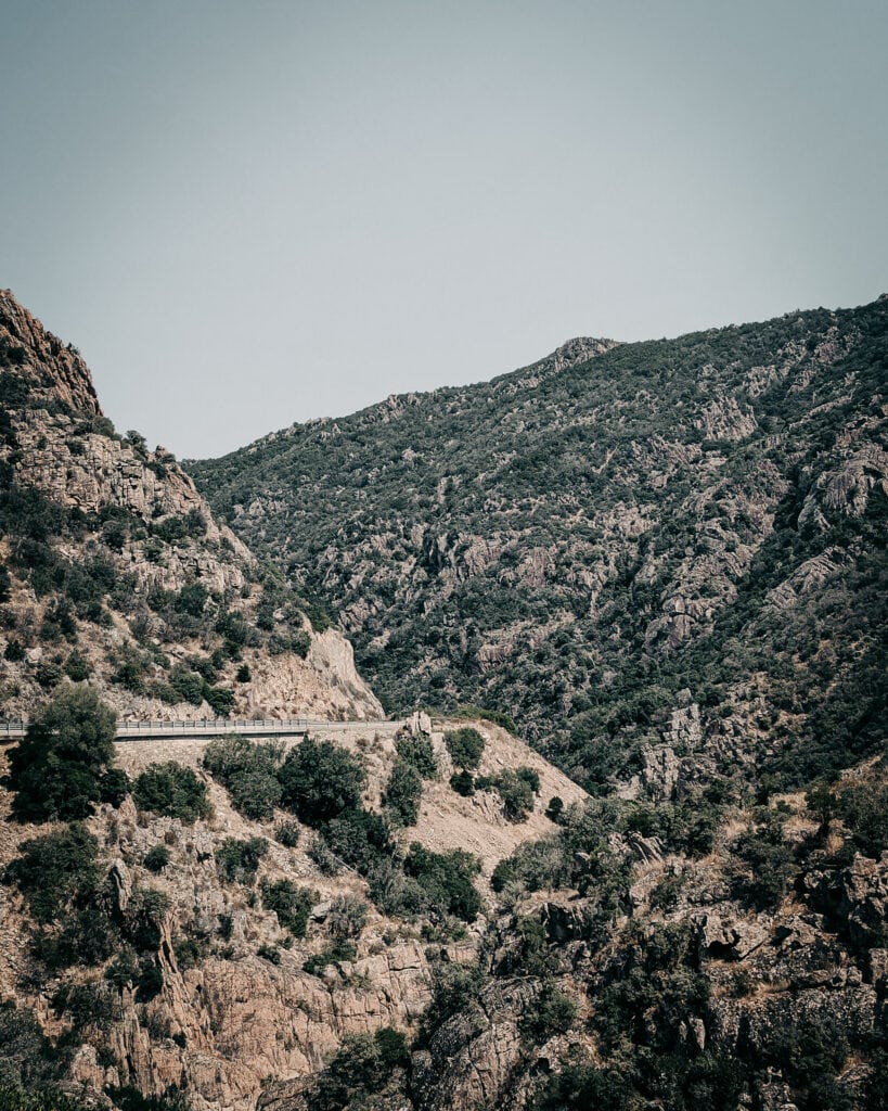 Mountain landscape with rugged terrain and winding road for adventure riding.