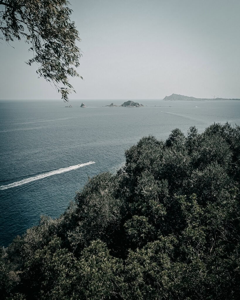 Beautiful coastal landscape with trees, sea, and distant islands.