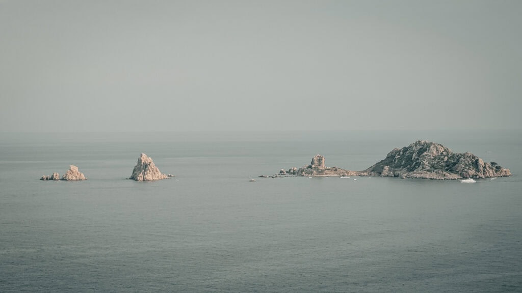 Scenic view of rocky islands in calm ocean waters under a cloudy sky.