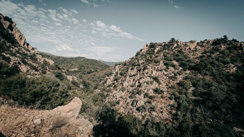Beautiful mountain landscape with rugged terrain and sparse vegetation under a partly cloudy sky.