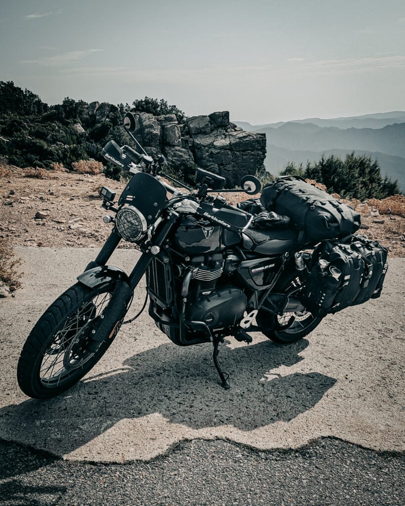 Black adventure motorcycle with luggage on mountain road during daytime.