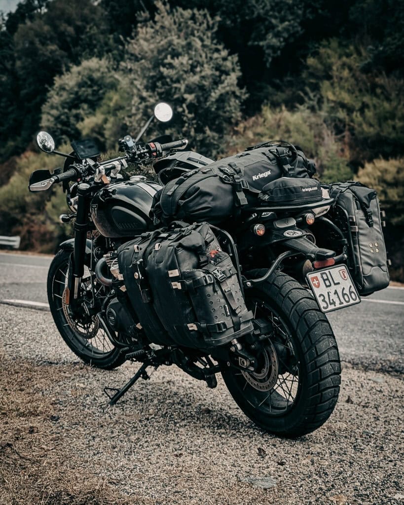Black cruiser motorcycle equipped with saddlebags and luggage on a scenic road.
