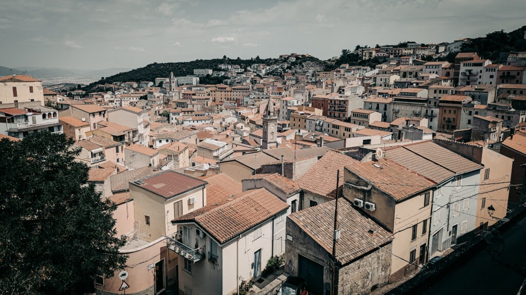 Panoramic view of a Mediterranean hillside town with terracotta roofs and narrow streets.