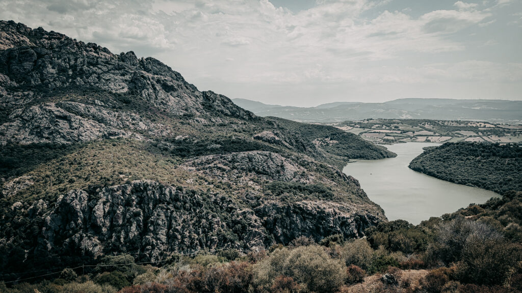Panoramic view of river winding through hills and mountains in black and white.
