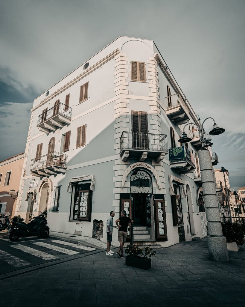 Historic white building with balconies and street view in Italy.