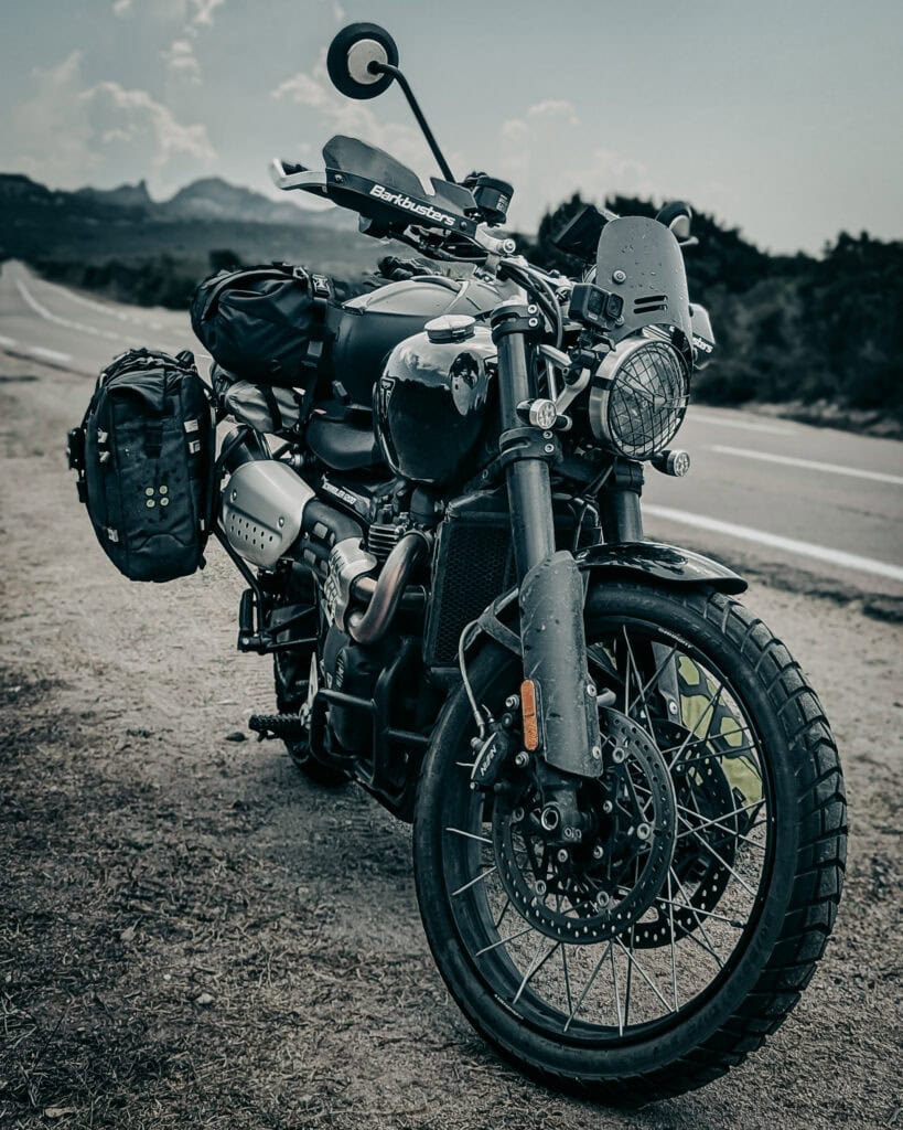 Black adventure motorcycle with gear on a scenic road.
