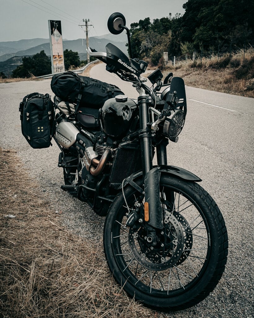 Black adventure motorcycle with gear parked on mountain road.