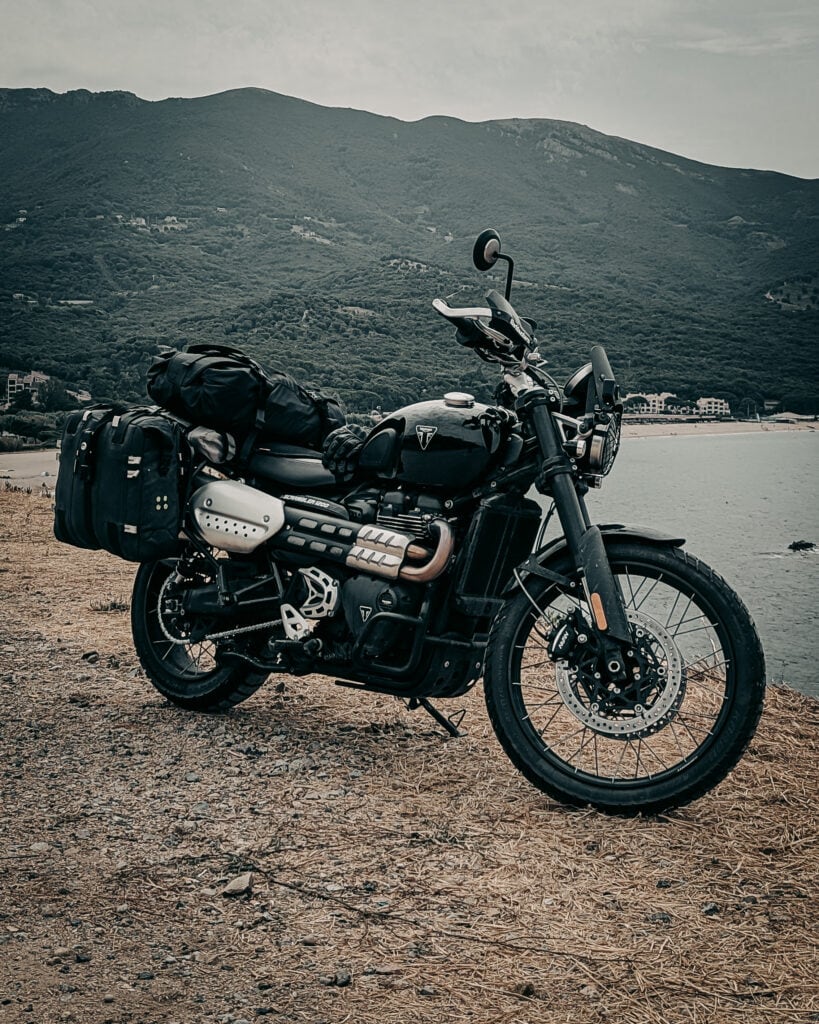 Black adventure motorcycle with luggage on scenic lakeside background.