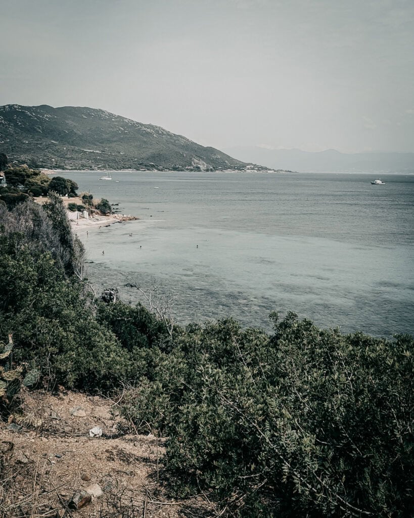 Beautiful coastal view with mountains, water, and greenery in a serene setting.