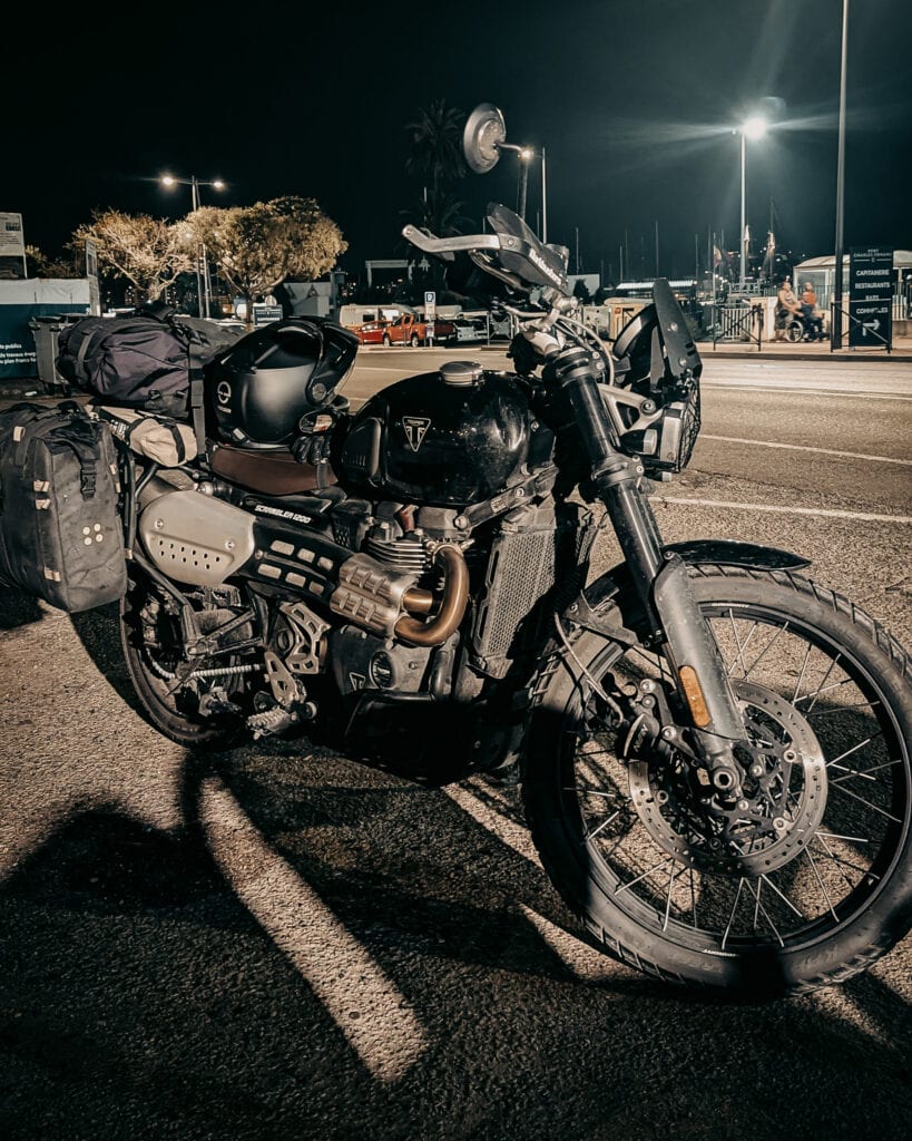 Black adventure motorcycle with gear parked at night on the street.