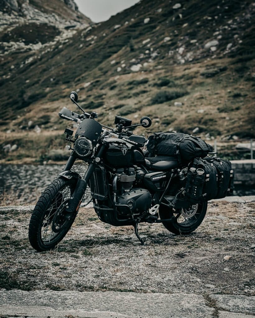 Black adventure motorcycle with luggage on mountain road.