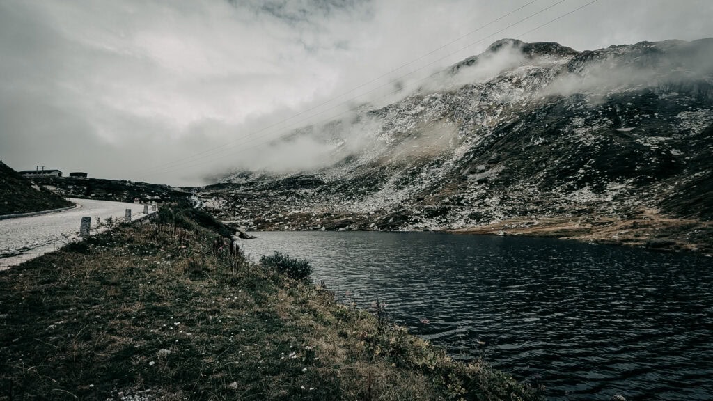 Mountain lake surrounded by rugged terrain and misty clouds.