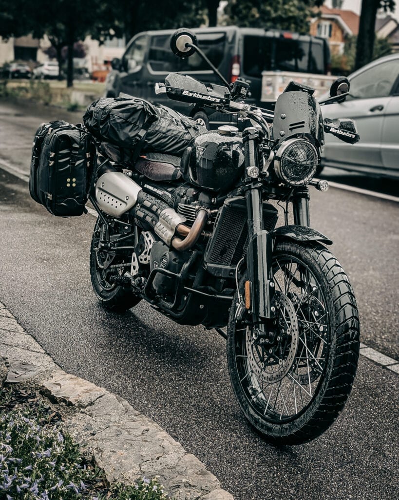 Black adventure motorcycle with gear parked on city street for travel.